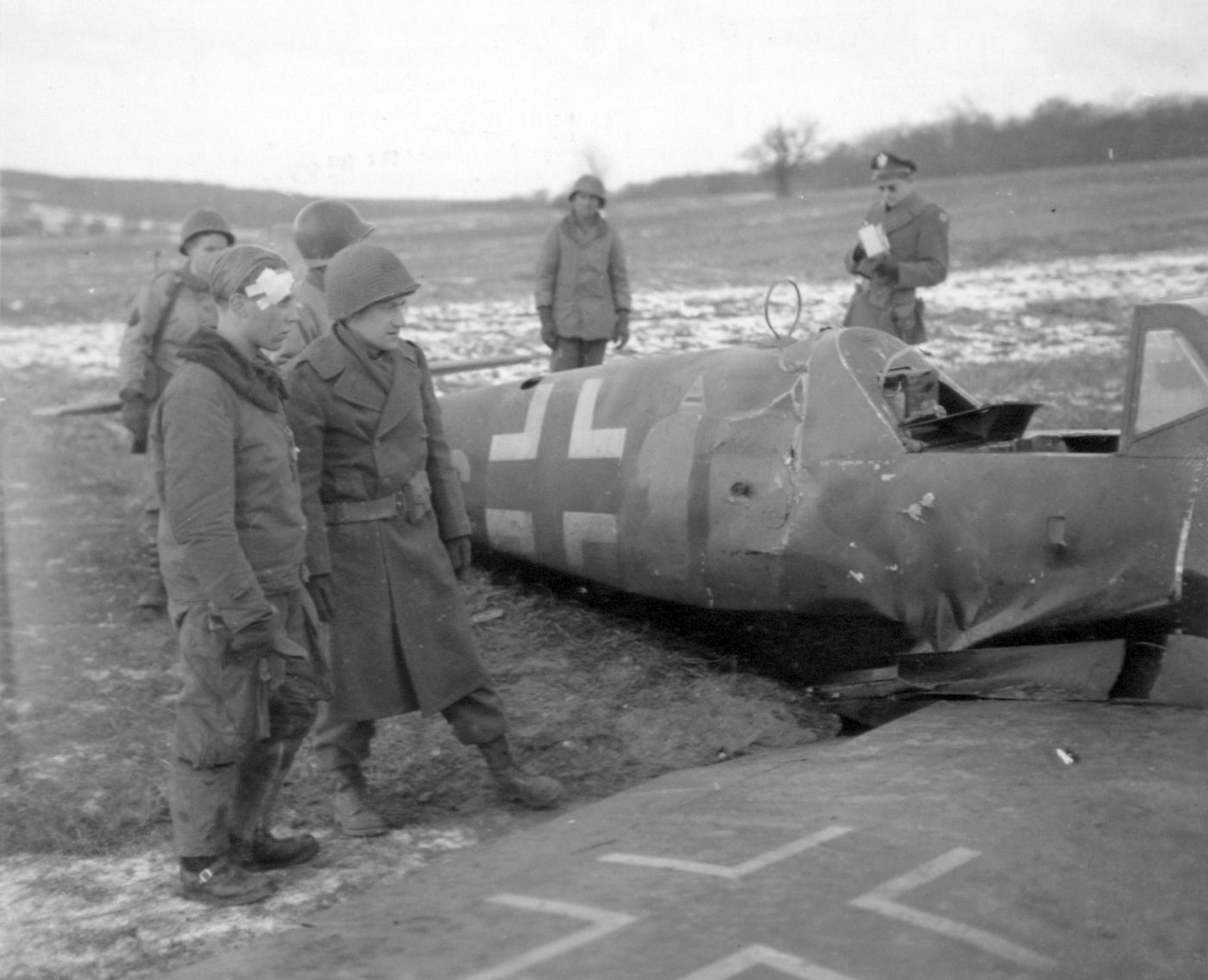 1945年1月,法国摩泽尔省哈尔斯特罗夫附近,一架被击落的德军 Bf 109 战斗机,一名被俘的德军飞行员在座机旁。