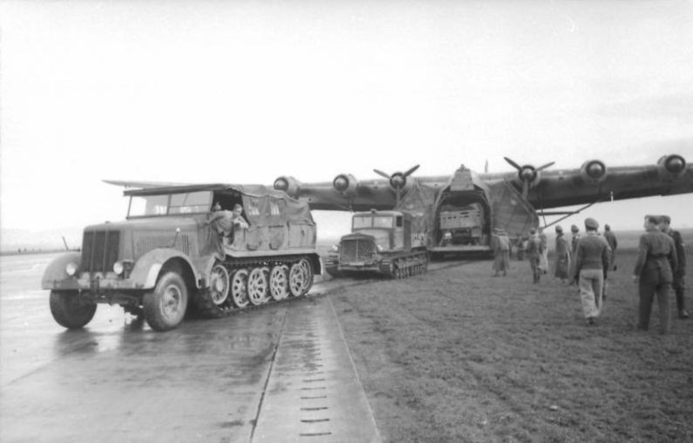 1943年突尼斯战场上，多辆牵引车（Zugmaschinen）在机场地面牵引着庞大的 Me 323「巨人」。随着「突尼斯战役」进入攻坚阶段，德国空军的地中海补给线日益艰险，1943年4月22日一支由27架 Me 323 组成的编队在西西里海峡上空遭喷火式与P-40战斗机拦截，21架当场被击落，这场惨败使 Me 323 部队元气大伤，剩余机群不久后便撤回本土直至1944年退役。