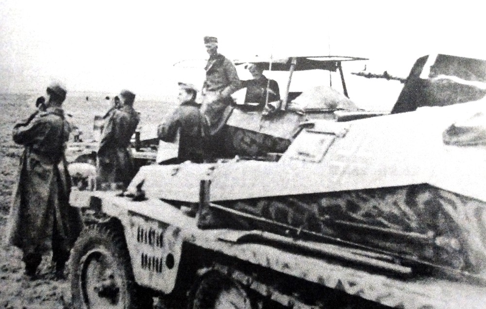 1942年,东线苏联战场,2辆德军(不明单位)Sd.Kfz.250/3 Ⅳ(Alt)型半履带装甲通讯指挥车的指挥官正在停下的车辆前观察前方战况。