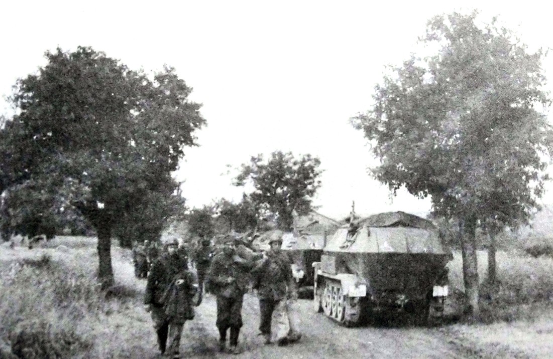 1940年,西线战场,停靠在比利时公路上的一队德军Sd.Kfz.251/1 Ausf.A型半履带装甲运兵车,车旁走过的是被俘的法军士兵。