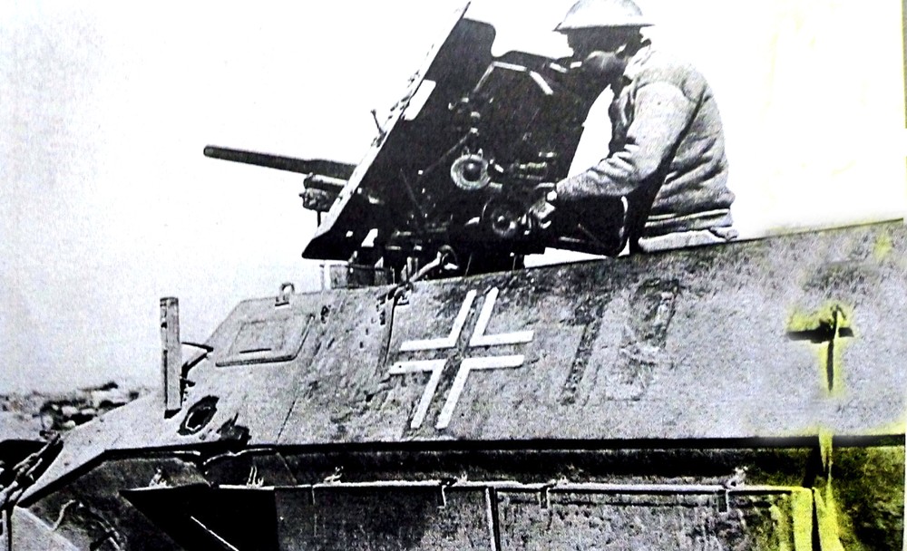 1942年,非洲战场,一辆被英军缴获的德军251/10中型半履带装甲炮车,车上一英军正在检查炮车上的37毫米火炮。