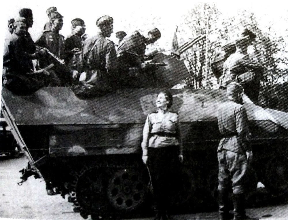 东线战场,苏军将一辆缴获的战场改装型的德军Sd.Kfz.251/21半履带装甲自行防空炮车改作运兵车用,车旁站着一名满脸笑容的指挥交通的女兵。