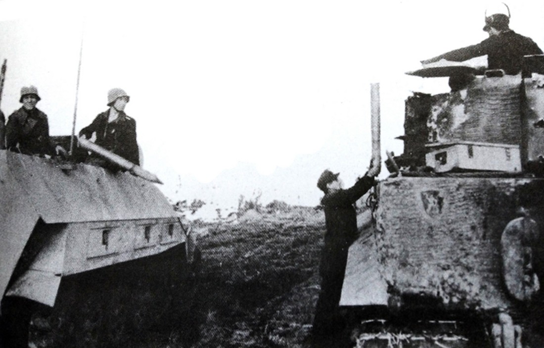 图中左边是一辆德军作弹药运载用的Sd.Kfz.251/4 Ausf.D型半履带装甲车,车组的弹药手正在将炮弹传送给一辆虎式坦克作弹药补给。