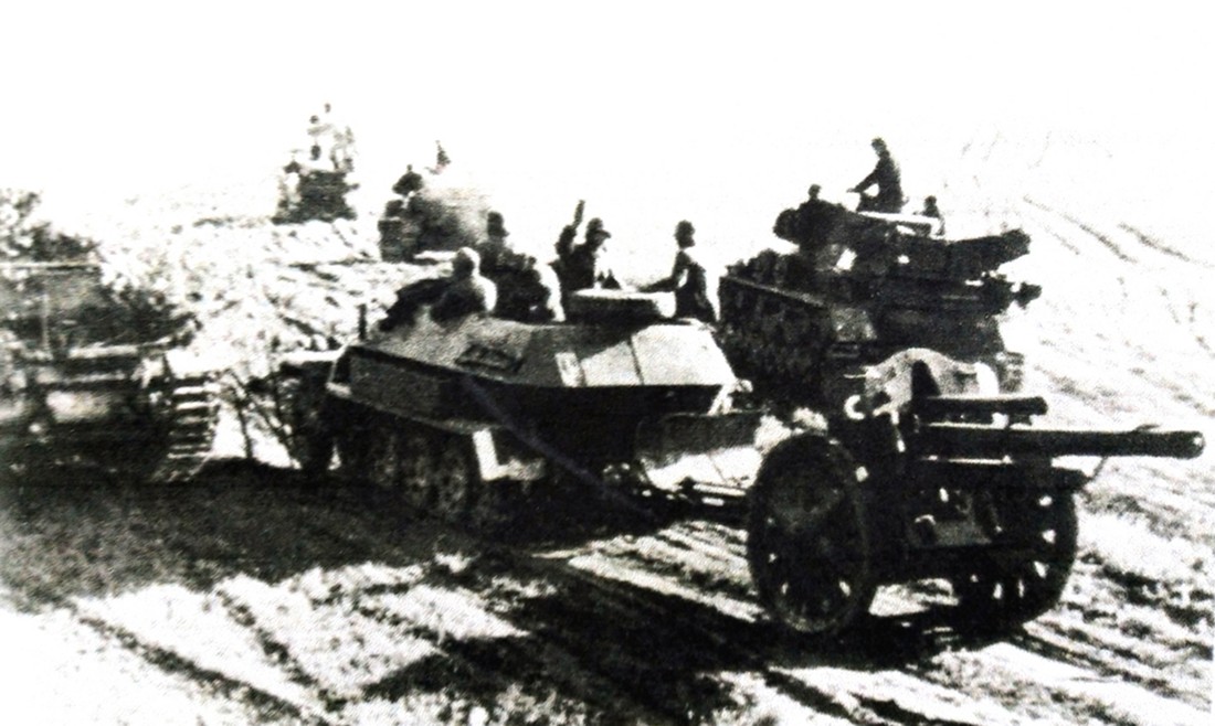 1940年5月,西线战场法国地区,一辆德军第7装甲师炮兵团的Sd.Kfz.251/4 Ausf.A型半履带装甲火炮牵引车牵引着一门105毫米口径LeFH 18型轻榴弹炮与多辆德军坦克一起向前线进发。