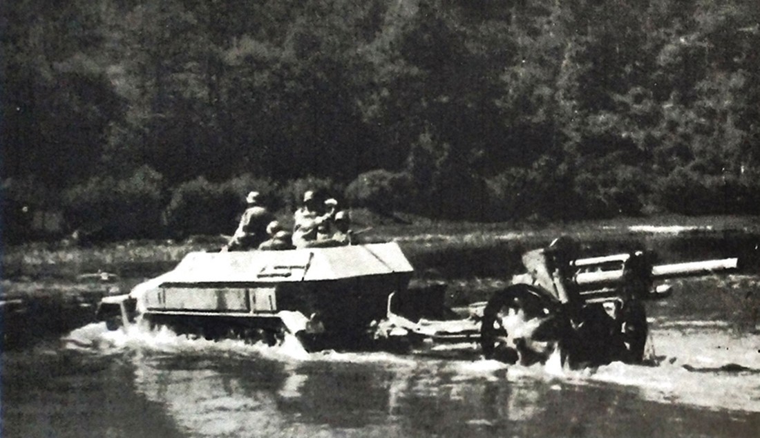 一辆牵引着一门105毫米口径LeFH 18型轻榴弹炮的德军Sd.Kfz.251/4 Ausf.B型半履带装甲火炮牵引车正在涉水越过小河。