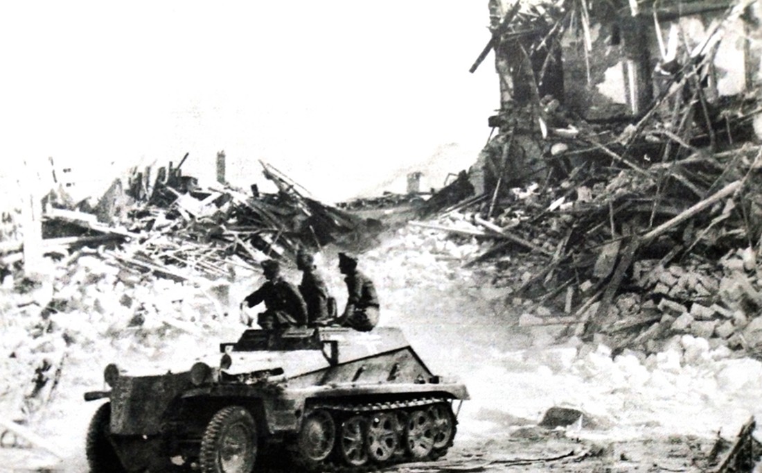 1942年6月,东线苏联战场塞瓦斯托波尔地区,德军第190突击炮营的一辆Sd.Kfz.252半履带装甲弹药运载车载着3名德军士兵驶过一处废墟。