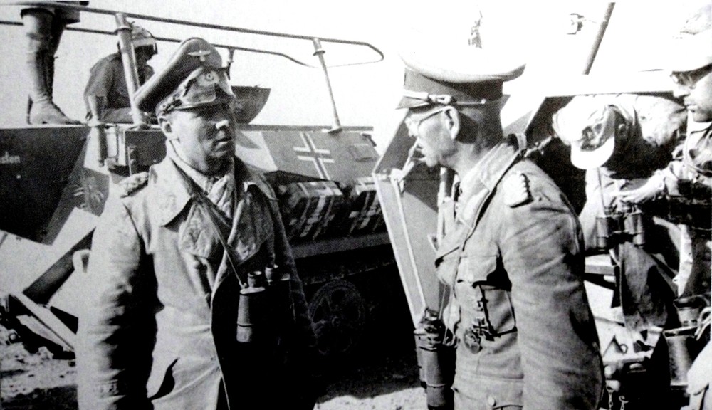 1941年,北非战场,德国非洲军团最高指挥官隆美尔元帅正站在一辆253型半履带装甲炮兵观测车前对一德军军官作指示。