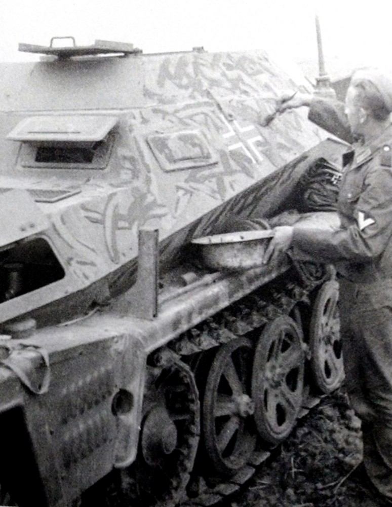 一名德军正在为一辆Sd.Kfz.250/253型半履带装甲炮兵观测车涂上伪装图案。