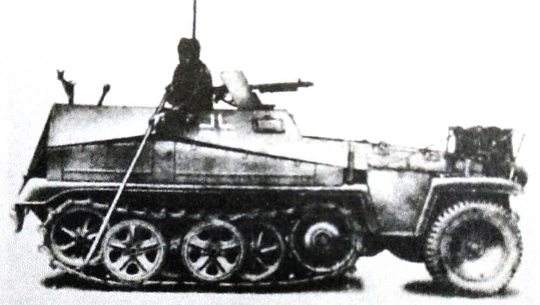 一辆德军小型Sd.Kfz.250/2半履带装甲野战电话布线车正在作布线操作，车上的一名布线兵正用一条长杆将车头滚轴的线缆往地上铺设。