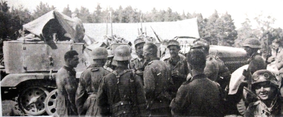 1941年6月,爱沙尼亚,德军402摩托化营的士兵们站在一辆比较少见、配有炮身和加长履带的5吨级Sd.Kfz.6/1半履带牵引车前。