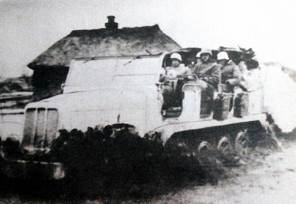 1941年~1942年间,东线苏联战场,一辆德军Sd.Kfz.6半履带牵引车在苏联乡村路上行驶。由于行驶速度较快,拖车在泥路上带来了一阵滚滚烟尘。