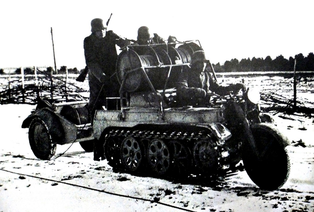 显而易见,用Sd.Kfz.2小型半履带车来布放野外线路是比较方便的。图中这辆Sd.Kfz.2小型半履带车上装有重型野外电缆放线滚筒,车后还牵引着一个装有电缆滚筒的拖卡,1名士兵驾驶车行进,2名士兵站在车上进行布线作业。