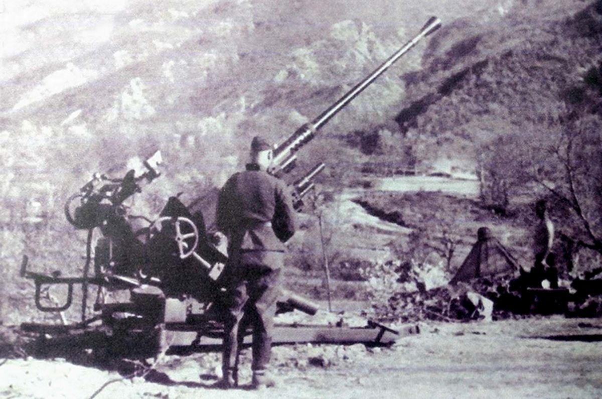 这是安装在山区地带的德国空军高炮部队的一门37毫米Flak36型高射炮，德军将这门炮安装在空旷的地面上，目的是为了方便观察空中目标和为高射炮提供一个尽可能宽的射击空间。在无战事的时候，炮班士兵在炮旁支起了帐篷，似乎在享受田园生活。