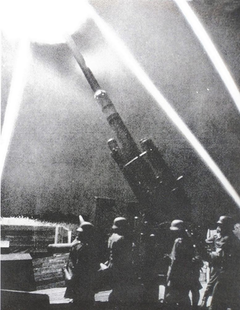 二战德国本土,夜间,德军空军高炮连的一门88毫米高射炮正在探照灯的指引下向空中目标射击。