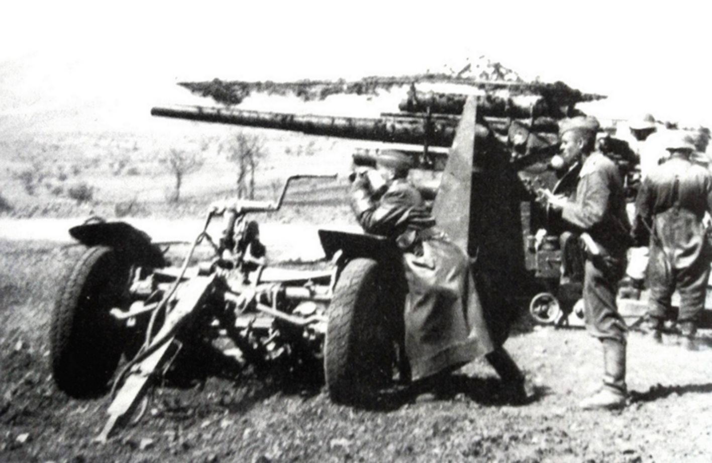 1944年1月,西线意大利战场安齐奥地区,一门德军高炮营的88毫米Flak18高射炮班正在阵地中准备迎击登陆的美军。一炮兵指挥官正伏在火炮挂车(Flak18专用的Sd.Anh.201特种挂车)上,用望远镜对前方进行观察。