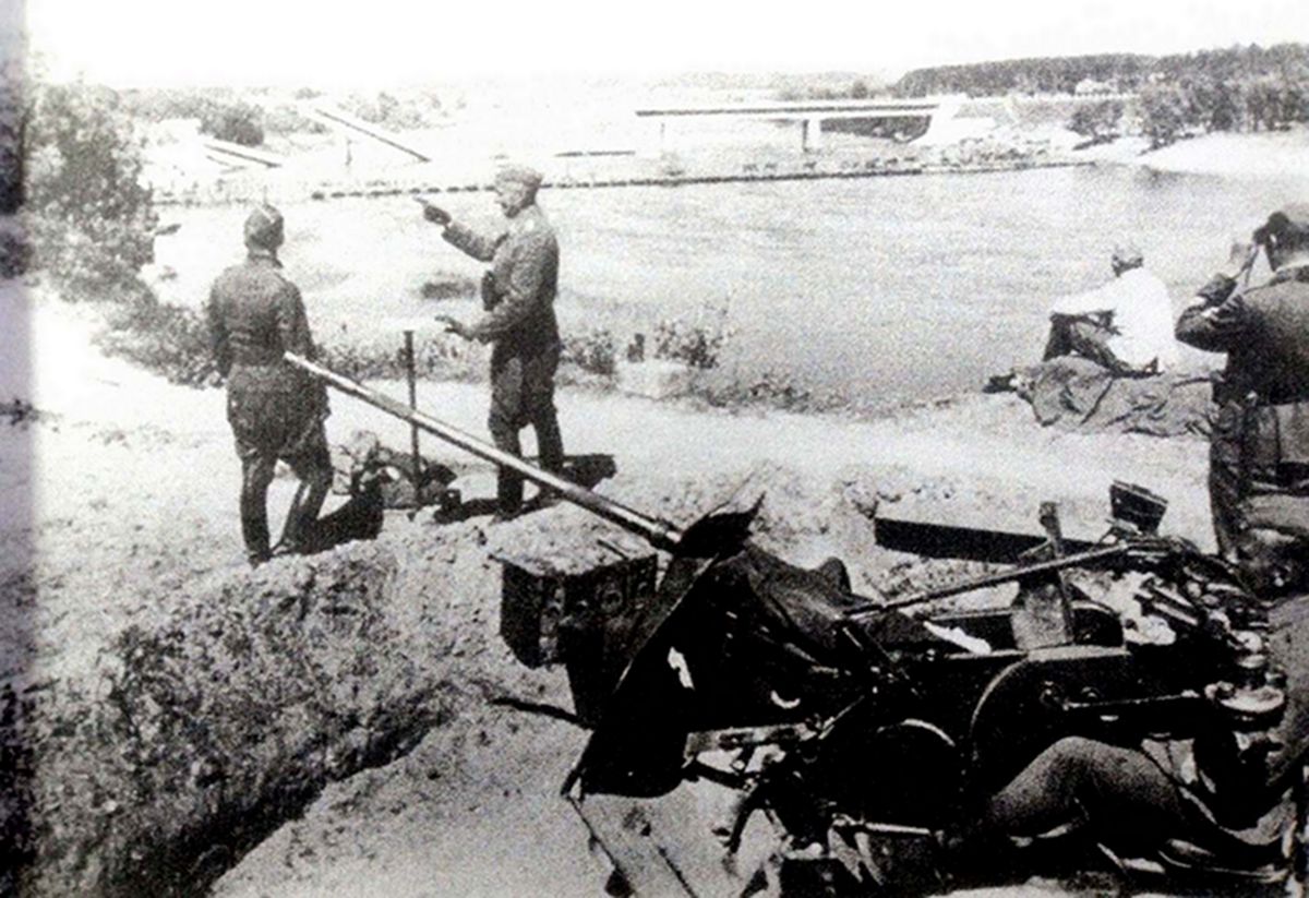 1941年,在尼曼河流域地区(Niemen)已被炸毁的一条军事桥梁附近,德军炮兵部队的一门20毫米Flak30型高射炮在构筑好的阵地上进行战斗准备,一军官正在作战斗部署。