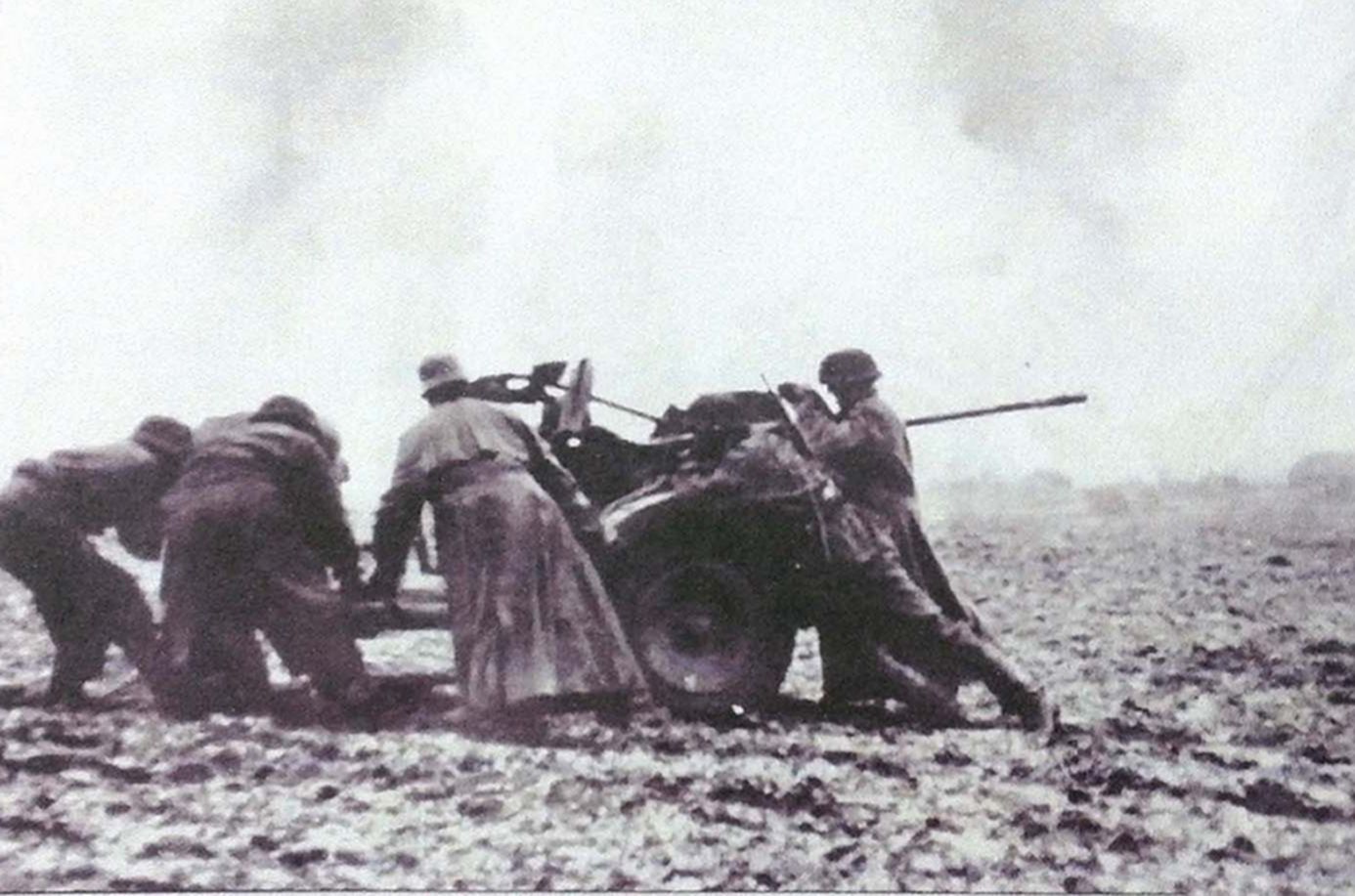 1941年冬天,东线苏联战场,穿着大衣和伪装服的德国武装党卫军多名士兵正在泥泞地上吃力地将一门20毫米Flak30型高射炮转移到新的阵地上。尽管该炮重量较轻,仅有770公斤,但在这样的环境下,这些人使出尽全力也感到困难。