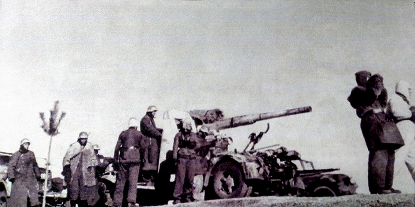 1943年冬季,东线苏联战场,一门已作好战斗准备的德军88毫米Flak36/37高射炮,炮前的几名军官正观察前方远处的苏军坦克动向;该炮旁边还停着一辆半履带装甲车,可知该门炮是刚从牵引车解下,炮身还在移动车架上。