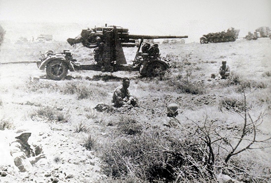 1941年夏天,非洲战场利比亚地区,在驻扎地休息的德国空军第33高炮团第1营的一门88毫米Flak36高射炮及其炮班成员。