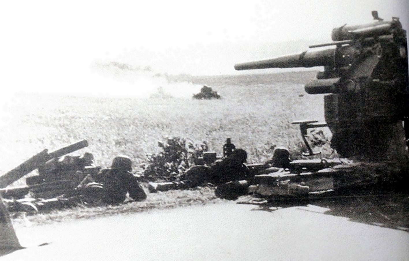 1941年7月,正与苏军坦克作战的一门德军88毫米Flak36高射炮,远处还可以见到被击中起火的苏军坦克。