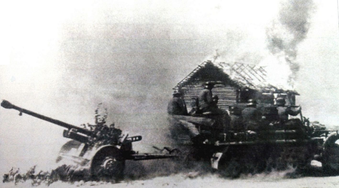 1944年末,东线苏联战场,一辆Sd.Kfz.10型半履带装甲车牵引着一门50毫米Pak38型反坦克炮在俄罗斯南部一处熊熊燃烧的村庄旁驶过。在二战后期,不少德军反坦克连队仍在用50毫米Pak38型反坦克炮来对抗苏军强大的坦克战车。注意:图中的50毫米Pak38型反坦克炮的轮胎有点奇怪,不像是通常的橡胶轮胎。