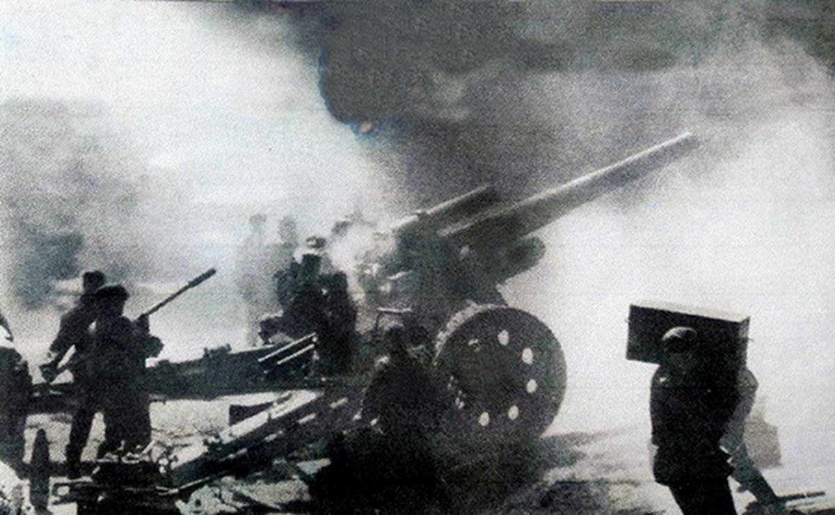 德国武装党卫军炮兵部队的一个火炮阵地，阵地中的150毫米s.FH18榴弹炮正在向远处的敌军火炮阵地开火，战斗中，一名炮兵正在忙碌地搬运弹药。