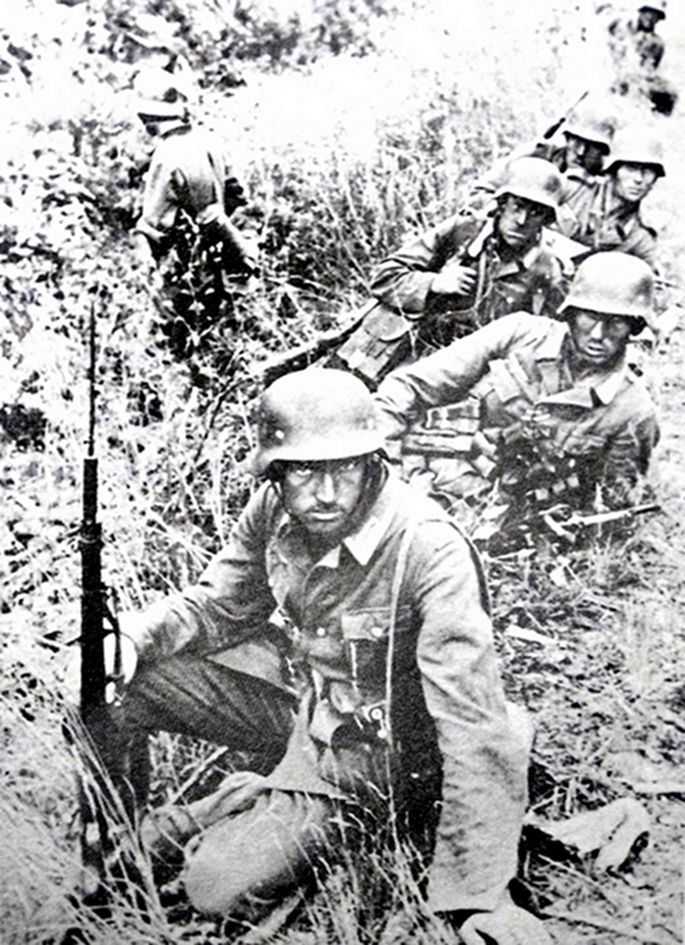 1941年6月,东线苏联战场,「巴巴罗萨」行动中,隶属德国国防军第18军的一队士兵正利用战斗间隙中作短暂休息,坐在最前面的一名士兵手持的是上了刺刀的98K步枪。