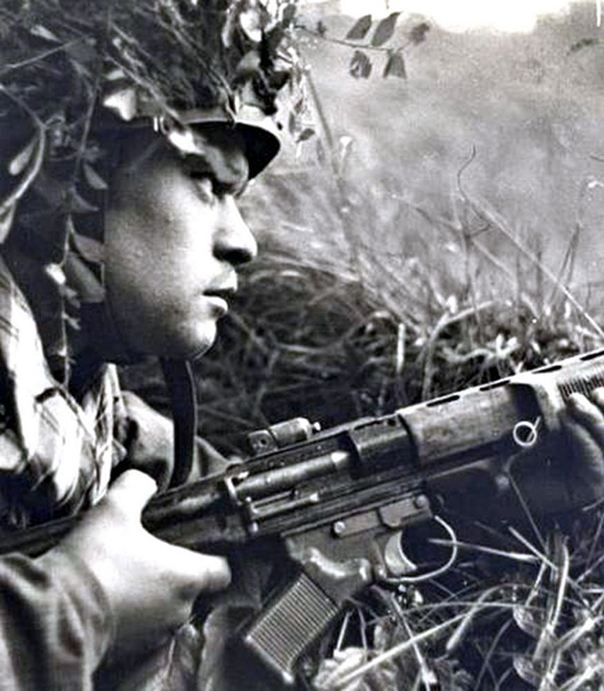 西线战场上一名德军伞兵以草丛为掩护,持FG42伞兵步枪聚精会神地注视前方,随时准备投入战斗。