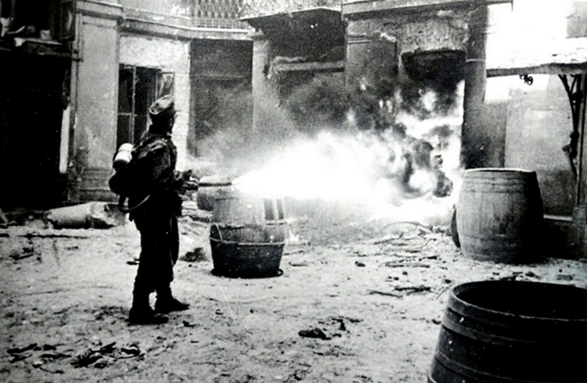 1944年,波兰华沙,一名装备41s型火焰喷射器的德军士兵向隐藏在房屋内的华沙起义者喷射火焰。