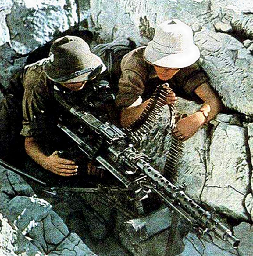 1942年，非洲战场，德国非洲军团的一个MG34机枪组在一个石堆阵地中作战斗警戒。