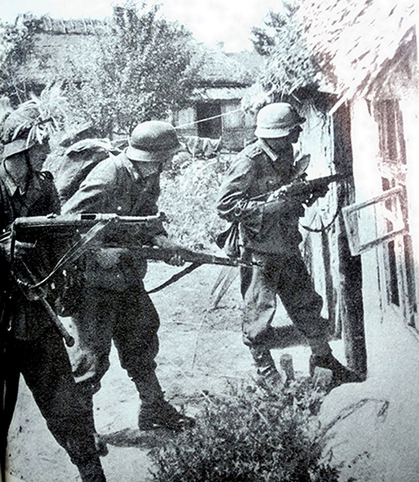 1941年夏天,东线苏联战场,手持MP38/40冲锋枪的德军士兵正在搜索躲在农舍中抵抗的苏军。