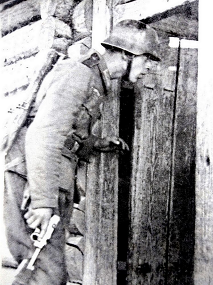 1941年,东线苏联战场,一名德国军官手持一支鲁格P08手枪准备进入一所农舍内搜查。