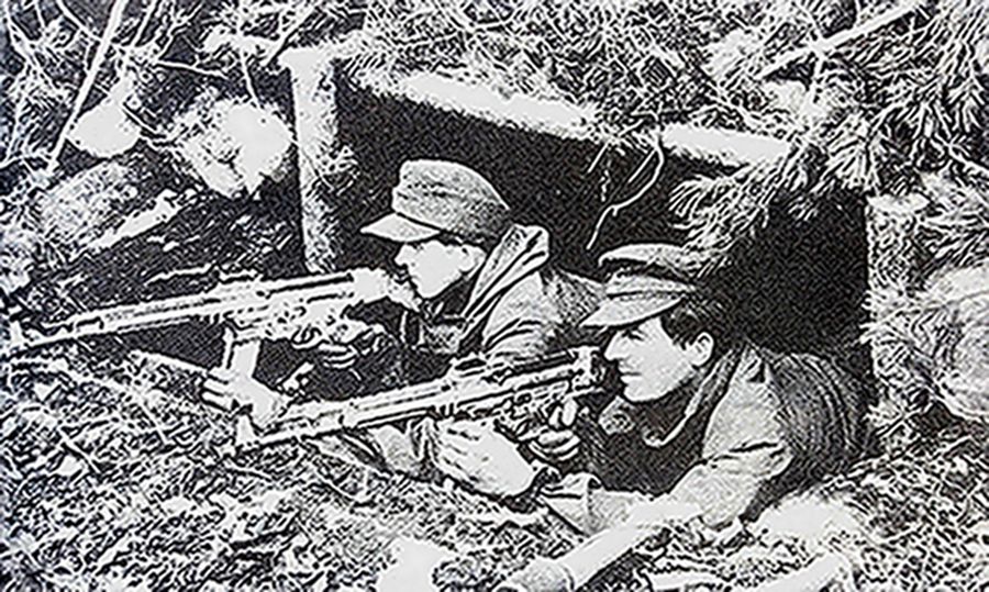 1945年,德国本土防御战中,隐藏在掩体阵地中的两名德军士兵手持StG44突击步枪警惕地注视着前方,作好战斗准备。