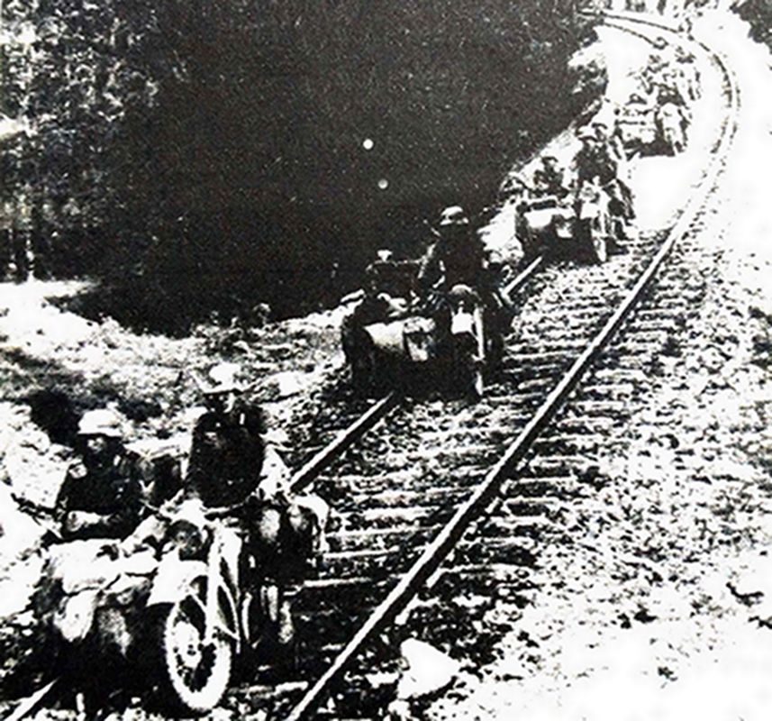 1941年4月，巴尔干半岛希腊，隶属德军第5装甲师第55摩托化营的一队宝马 R12摩托车队正沿着铁路行进。摩托车巧妙地将铁轨置于车身与边厢的两轮之间，可见德军的摩托车手还是掌握了较好的驾驶技能。