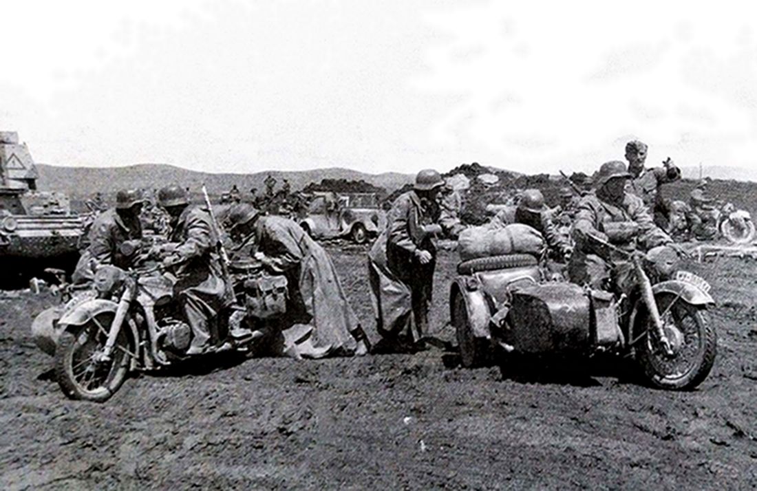 1941年希腊地区，德军一支宝马 R12军用摩托车部队在集结地准备出发，摩托兵们都穿着长雨衣，以在高速行驶中抵御寒风。