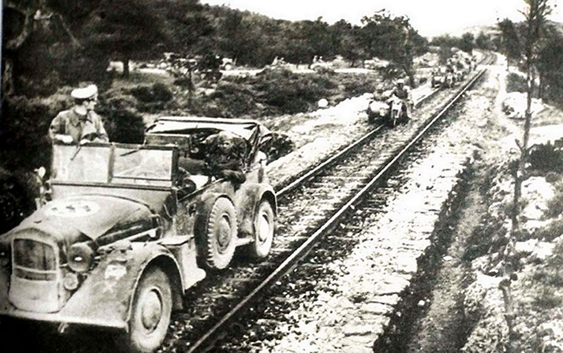 1941年5月,巴尔干半岛希腊,隶属德军第5装甲师机动步枪团的一辆霍希 typ 830 Kfz.15轻型指挥车正带领一支摩托车队沿着铁路线行进。