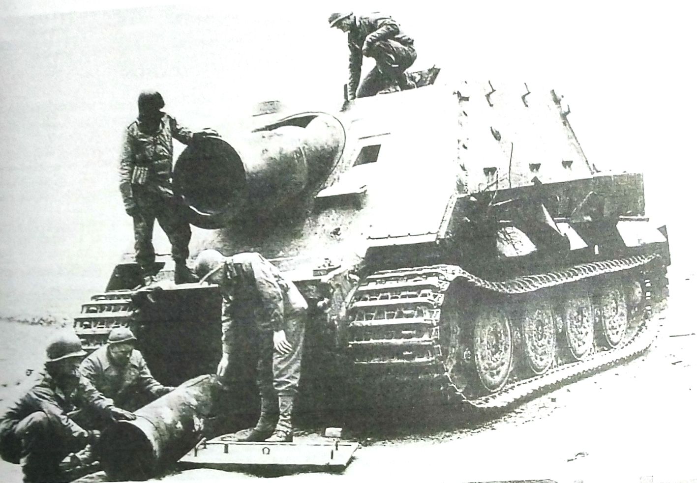 1945年3月,德国境内一辆被美军缴获的受损「突击虎」臼炮自行炮车。注意其炮管上的那块配重平面盘以及车身上配备的附加牵引杆。一群美军士兵正在认真观察该炮车与炮弹。