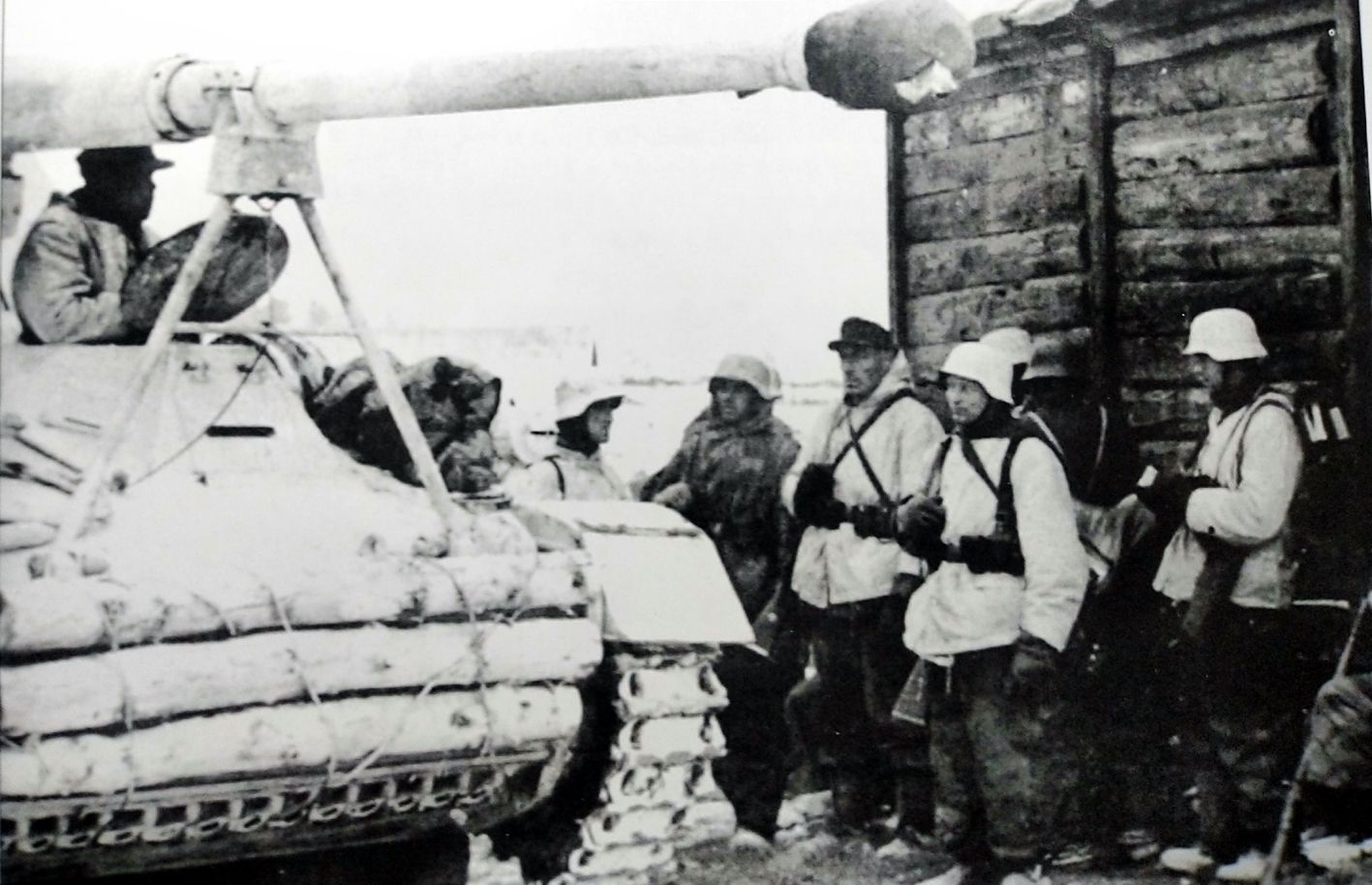 1943年冬季，东线苏联战场，一辆隶属德军第519重型反坦克营的88mm「犀角」自行反坦克炮车。该车车体前部捆绑着一些木桩作增强防护用，车体已涂上白色冬季伪装，炮口也用布封死以防异物进入炮管内。炮车旁边是德军步兵，他们一身冬装表明该部队已完成了冬季后勤补给。