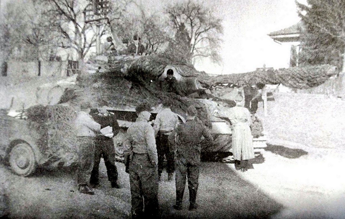 1945年3月德国本土战场，653重装甲歼击营第2连一辆「猎虎」重型坦克歼击车渡过莱茵河后在一墓地待命，这部「猎虎」全车（包括炮管）已罩上一层伪装网。