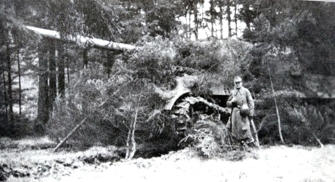 1944年冬天，653重装甲歼击营第3连一辆在树林中待命的「猎虎」重型坦克歼击车，该车用树枝等作了伪装，一名德军士兵在车旁警卫。