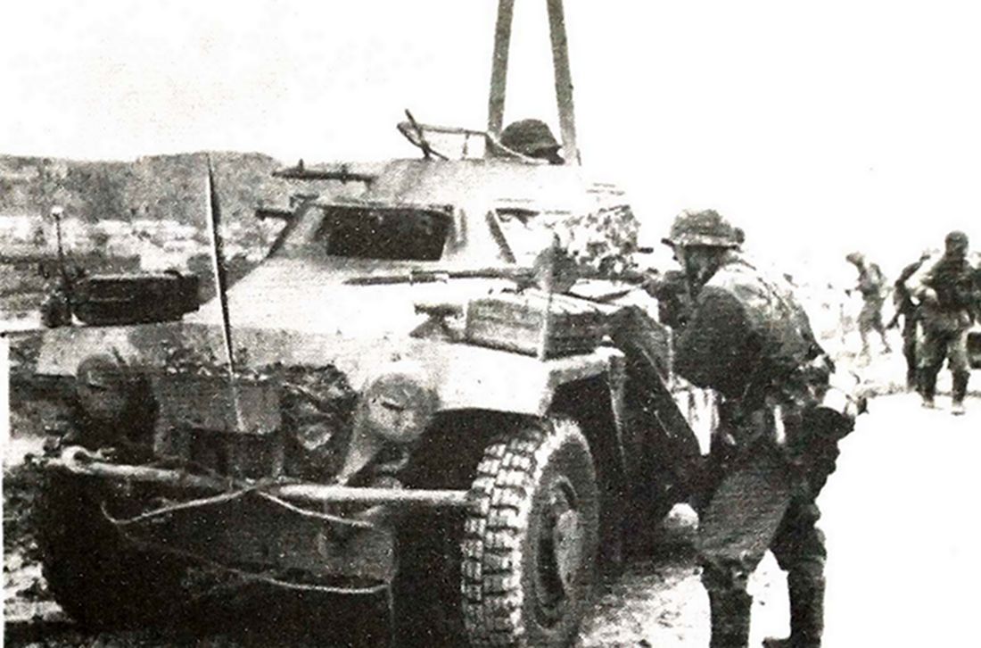 这是在作战状态中的一辆德军Sd.Kfz.221型4轮装甲侦察车，一德军士兵以该车作掩护进行射击。