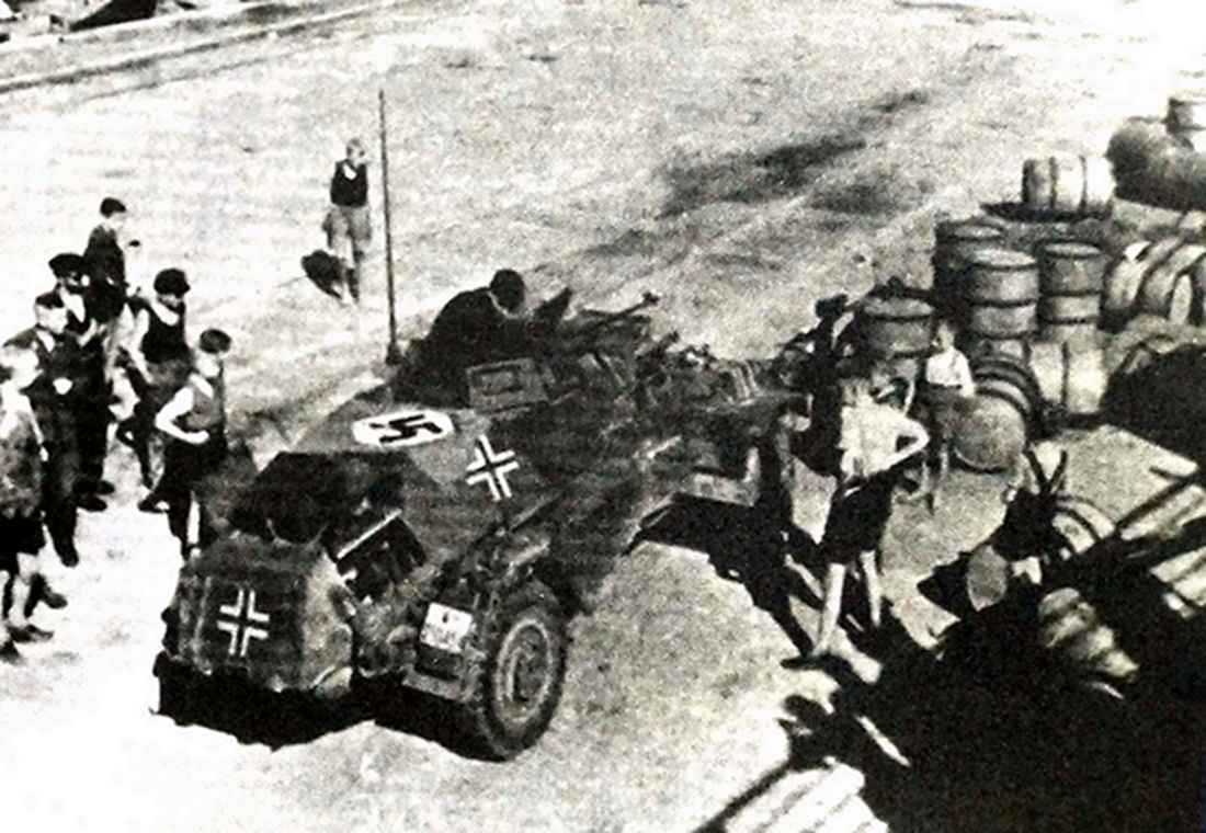 1943年，一辆德军Sd.Kfz.221型4轮装甲侦察车正在补充物资（油料），该车车身上方铺着一面万字旗以作防空识别，看来这辆4轮装甲车即将要开赴前线。