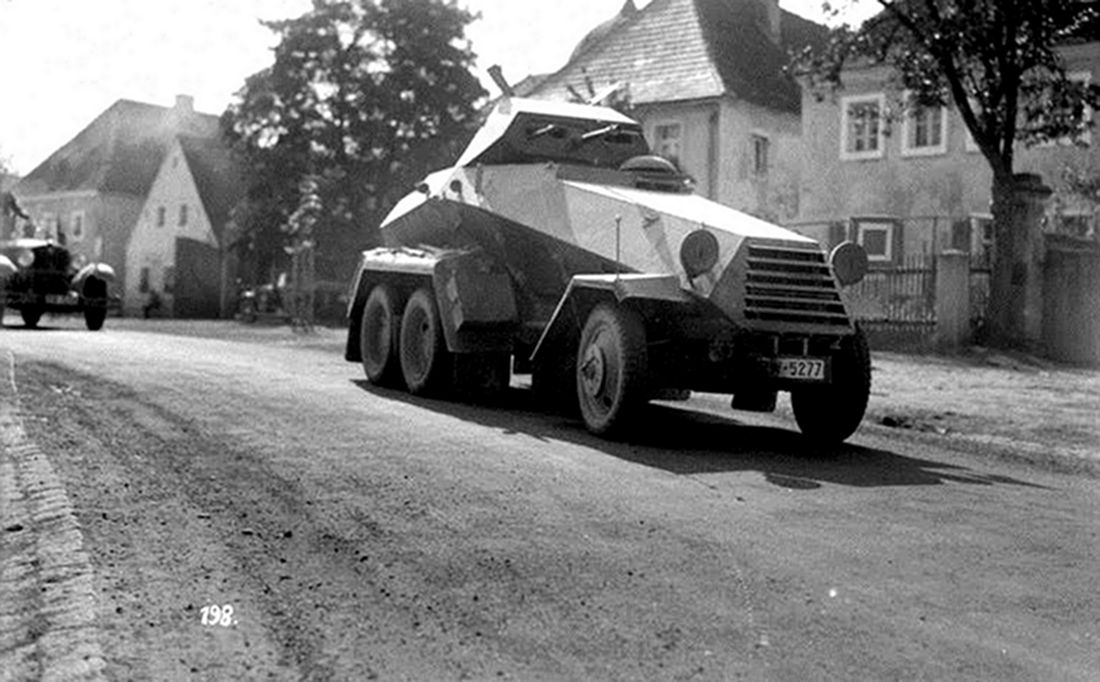 一辆Sd.Kfz.231型6轮装甲侦察车正在小镇路上行进。此车车体十分新净，可清楚见到车体与炮塔正面结构与武器，可能是刚出厂而未上过战场的新车。