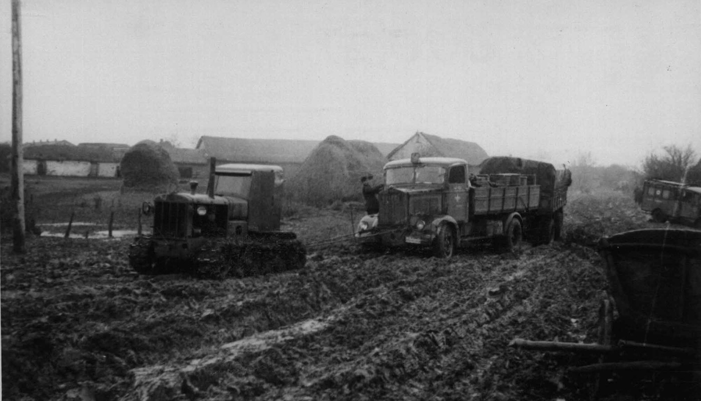 1942年,东线战场,一辆隶属德军的民用版Lancia 3Ro 464系列轿车在一辆缴获的苏联农用拖拉机帮助下驶过一条泥泞道路。