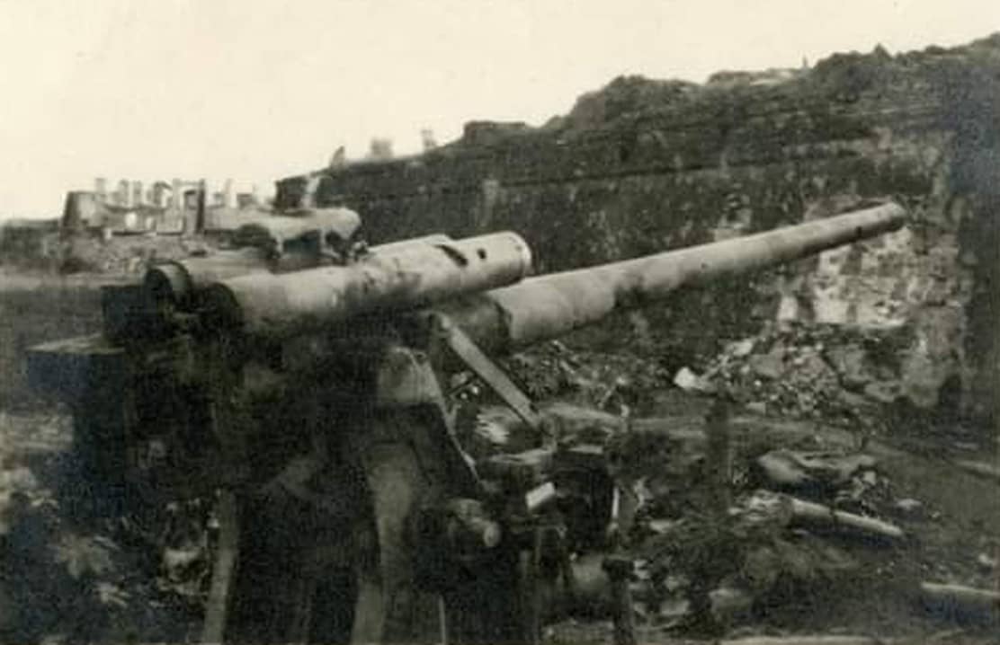 1945年,菲律宾,一门被美军缴获的日军九九式88毫米高射炮,其部署在遭轰炸损毁的混凝土建筑物旁。