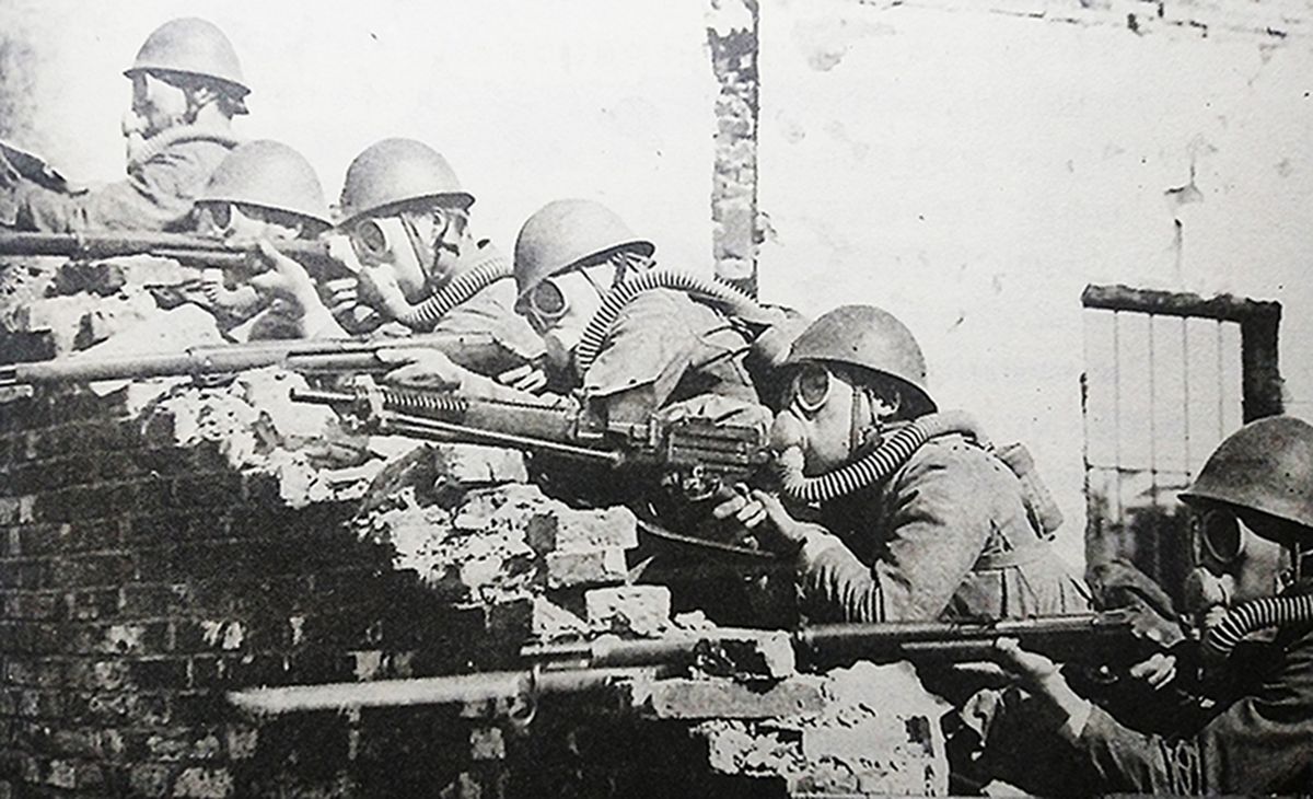 1938年,中国抗日战场,在武汉会战中,日军使用了毒气攻击中国抗日军队。图为戴着防毒面具的日军正在用11式轻机枪和三八式步枪向中国抗日军队阵地射击。