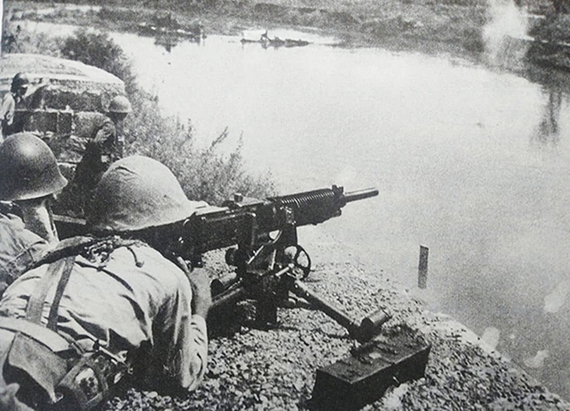 1941年9月,中国抗日战场,长沙会战期间,湖南省新市同乐桥地区,日军第4师团的一挺九二式重机枪正在向河对岸射击,压制中国抗日军队的火力点。
