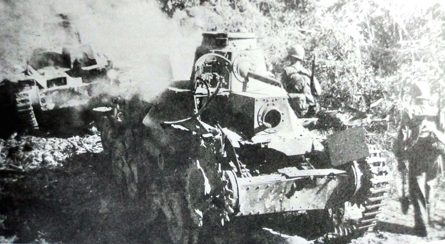 1944年，太平洋战场关岛，一队美军在被击毁的日军95式轻型坦克旁经过。
