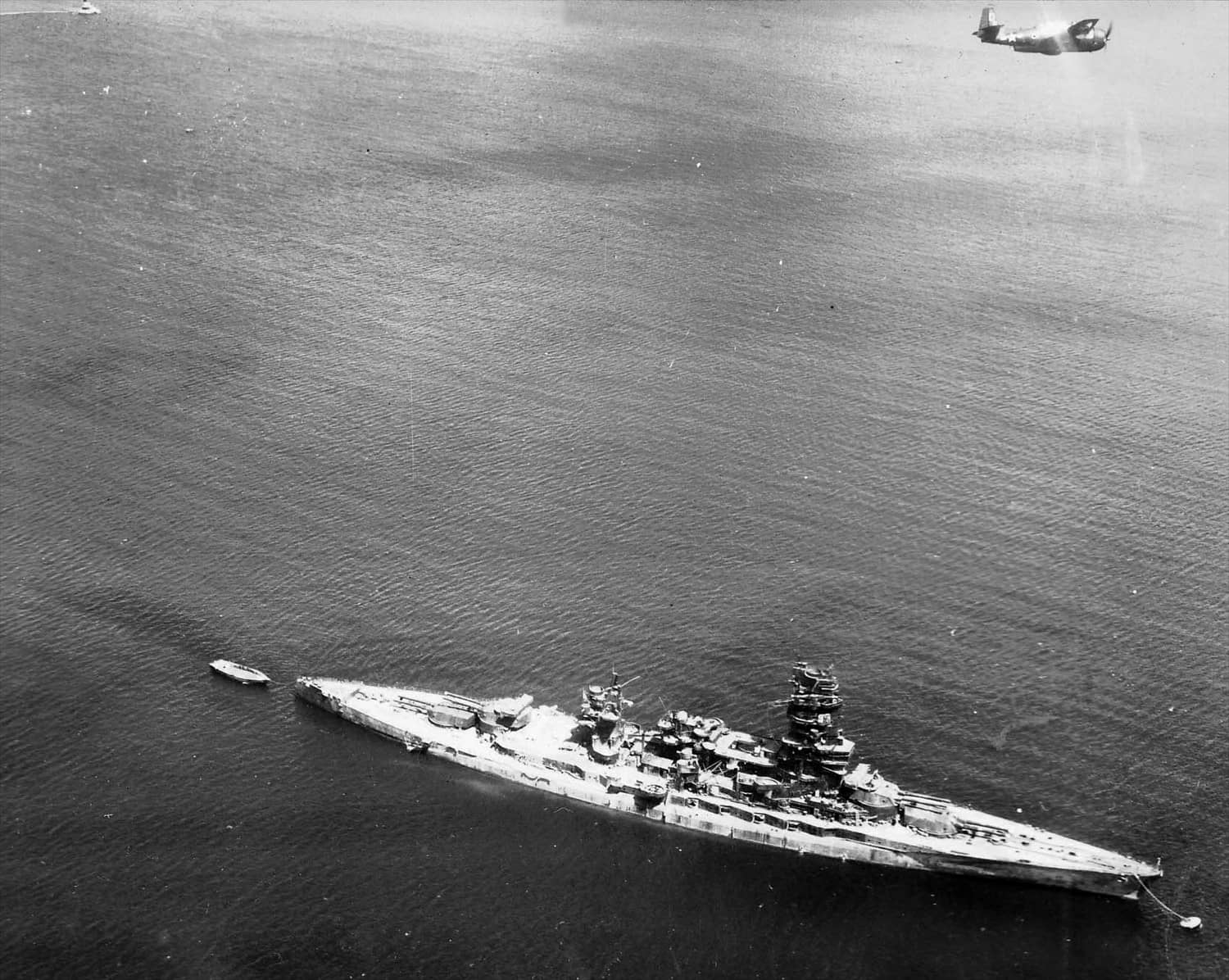 一架来自「独立」号(USS Independence,CVL-22)航空母舰第27鱼雷攻击中队(VT-27)的美国海军格鲁曼TBM-3「复仇者」式飞机,飞越横须贺海军基地的日本战列舰「长门」号上空;拍摄时间可能是在日本投降前后的1945年7月至8月间。