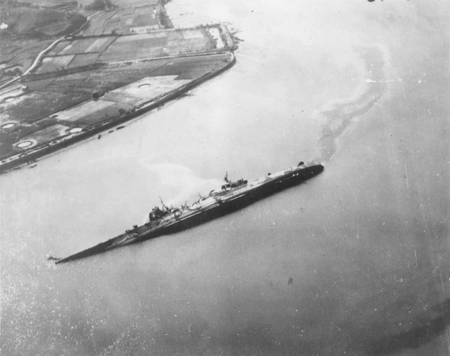 1945年7月28日,「吴港空袭」后倾覆于吴港浅水区的日本轻巡洋舰「大淀」号残骸,由美军「黄蜂」号(CV-18)航母舰载机拍摄。该舰四天内身中8枚炸弹,右舷进水失衡倾覆,约300名乘员战死。